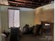 Unfinished room with exposed structure and window covered with tarp, undergoing renovation at 119 Mitchell St, Salisbury, NC 28144
