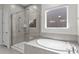 Modern bathroom features a walk-in shower, soaking tub, neutral tile, and a window at 12110 Anne Blount Aly, Huntersville, NC 28078