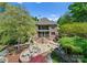 Expansive brick home showcasing tiered stone patio, lush landscaping, and outdoor seating at 12627 Ninebark Trl, Charlotte, NC 28278