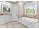 Bright bathroom featuring a soaking tub, vanity with mirror, and natural light from the window at 12627 Ninebark Trl, Charlotte, NC 28278