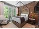 Bright bedroom with exposed brick wall, canopy bed, oversized windows, and cozy seating at 12627 Ninebark Trl, Charlotte, NC 28278
