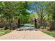 Long brick driveway leads to a private estate through stone gates and lush greenery at 12627 Ninebark Trl, Charlotte, NC 28278