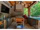 Well-equipped outdoor kitchen with stone accents, stainless steel appliances, and wood ceiling at 12627 Ninebark Trl, Charlotte, NC 28278