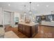 Open kitchen layout with a large island, stainless steel appliances, seamlessly flowing into the living room at 1407 Becklow Ct, Wesley Chapel, NC 28079