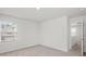 A bedroom with neutral carpeting, white walls, a window and a glimpse of the hallway at 14217 Wilson Mac Ln, Charlotte, NC 28278