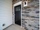 A close-up of the front door with stone siding and white trim around the door and siding at 14217 Wilson Mac Ln, Charlotte, NC 28278