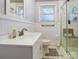 Clean bathroom featuring white wainscoting, a shower, a sink with vanity, and a toilet at 143 W College St, Stanley, NC 28164