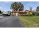 Charming single-story home with a red metal roof, lush landscaping, and a welcoming front entrance at 143 W College St, Stanley, NC 28164
