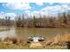 Lakeside backyard featuring a wood dock, lake access, blue skies, and mature trees at 233 Conifer Way, Shelby, NC 28150