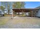 Open carport with wooden beams, concrete flooring, and a gravel driveway in the backyard at 2420 Kannapolis Hwy, Concord, NC 28027