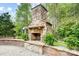 A stone outdoor fireplace provides warmth and ambiance with decorative ferns, brick, and a stone patio at 361 Nance Rd, Stanfield, NC 28163