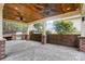 Covered outdoor kitchen featuring wood ceiling, ceiling fans, stone counters, brick accents, and a built-in grill at 361 Nance Rd, Stanfield, NC 28163