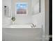 Soaking tub with chrome fixtures, and a window with bright natural light at 4607 Crewe Hall Ln, Waxhaw, NC 28173
