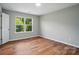 Bright bedroom with a window offers natural light and features a minimalist design with hardwood floors at 4607 Crewe Hall Ln, Waxhaw, NC 28173