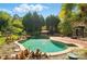 Outdoor pool area with a brick patio and umbrella, nestled amidst lush landscaping and mature trees at 4607 Crewe Hall Ln, Waxhaw, NC 28173