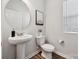 Modern powder room with pedestal sink, round mirror, and wood-look floors at 4754 Lakeview N Rd # 19, Charlotte, NC 28216