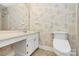 Bathroom featuring a single sink vanity with white cabinets, toilet, and patterned wallpaper at 6500 Wealdstone Ct, Mint Hill, NC 28227