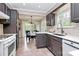 Charming kitchen with dark cabinetry, tiled backsplash, stainless sink, and a view into the dining area at 6500 Wealdstone Ct, Mint Hill, NC 28227