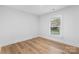 Empty bedroom with white walls, wood floors, and a window at 7009 Wrentree Dr, Charlotte, NC 28210