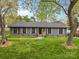 Traditional single-story home with a beautiful green lawn, tasteful shutters, and mature trees providing shade at 7009 Wrentree Dr, Charlotte, NC 28210