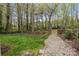 Backyard with lush green grass, stone walkway, and mature trees providing privacy at 7710 Epping Forest Dr, Huntersville, NC 28078