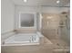 Luxurious bathroom with a soaking tub, tiled shower, and modern fixtures at 9582 Creighton Nw Rd, Concord, NC 28027