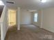Open-concept living space showcasing neutral walls, carpet flooring, and a convenient stairway access at 104 Mulligan Dr, Shelby, NC 28150