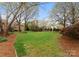 Lush green backyard with mature trees, manicured landscaping, and a serene, park-like atmosphere at 10809 Wicklow Brook Ct, Charlotte, NC 28277
