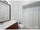 Bathroom featuring wood vanity, toilet, vanity mirror, and shower with blue shower curtain at 1114 Herrin Ave, Charlotte, NC 28205