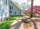 Green siding with white trim and a stone foundation accent the mature landscaping and charming walkway at 1206 Heatherloch Dr, Gastonia, NC 28054