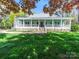 Charming home featuring a sprawling porch, lush green lawn, and mature trees at 1206 Heatherloch Dr, Gastonia, NC 28054