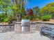 Outdoor grill with stone surround and stainless steel grill surrounded by landscaping and a seating area at 1206 Heatherloch Dr, Gastonia, NC 28054