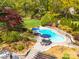 Aerial view of an inground pool with patio, tables, chairs, landscaping, and mature trees at 1206 Heatherloch Dr, Gastonia, NC 28054