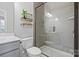 Modern bathroom featuring a glass-enclosed shower with gray tile, toilet, and decorative shelving at 1255 Fishing Creek Rd, Clover, SC 29710