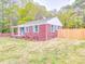 A charming red brick home is set back from the road with a large yard and a newly constructed wooden fence at 129 Wilson St, Chester, SC 29706