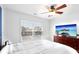 Comfortable bedroom featuring a ceiling fan, white bedding, flat screen television and a bright window at 13102 Petrel Pl, Charlotte, NC 28278