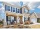 Charming two-story brick home with a welcoming front porch and well-manicured landscaping and partial blue sky at 13102 Petrel Pl, Charlotte, NC 28278