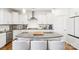 Modern, all white kitchen with stainless steel appliances, island with barstool seating and hardwood floors at 13102 Petrel Pl, Charlotte, NC 28278