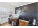 Home office space featuring a sleek desk, dark accent wall, and ample natural light at 13102 Petrel Pl, Charlotte, NC 28278