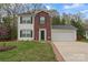Traditional home featuring red brick, attached garage, and a well-kept lawn with stone-lined flowerbeds at 140 Camforth Dr, Mooresville, NC 28117