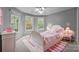 Bedroom features a pink patterned bed, a pink striped rug, and three windows with views of greenery at 17301 Glassfield Dr, Huntersville, NC 28078