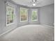 Bedroom showcasing 3 large windows overlooking backyard, gray walls, and neutral carpet with ceiling fan at 17301 Glassfield Dr, Huntersville, NC 28078