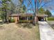 Charming brick home featuring a welcoming covered porch, lush landscaping, and a convenient carport on a sunny day at 206 Cliffside Dr, Kannapolis, NC 28081