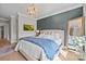 Stylish bedroom featuring a blue accent wall, hardwood floors, large mirror, and custom lighting fixture at 318 Montrose Dr, Waxhaw, NC 28173