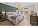 Cozy bedroom featuring a blue accent wall, hardwood floors, and a window with bamboo shades at 318 Montrose Dr, Waxhaw, NC 28173