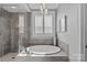 Soaking tub with glass shower, elegant light fixture, and large plantation shuttered window at 4038 City Homes Pl, Charlotte, NC 28209