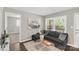 Comfortable living room features a grey sofa, wooden floors, and lots of natural light from large windows at 6057 Highway 97 Hwy, Hickory Grove, SC 29717