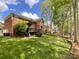 Spacious backyard featuring a deck, mature trees, green grass, and a fence line at 6114 Abergele Ln, Matthews, NC 28104