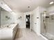 Bathroom with double sinks, tiled floors, glass shower, and an open door to the main bedroom at 6114 Abergele Ln, Matthews, NC 28104