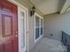 Inviting front porch with a red door, classic light fixture, and siding at 7524 Common Oak Dr, Stanley, NC 28164